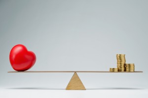 Red heart shape and money coins stack balancing on a seesaw